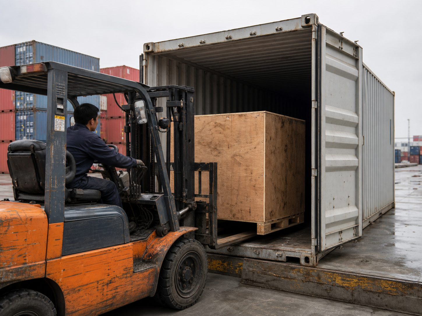Forklift loading a weathered plywood export crate into an unbranded shipping container